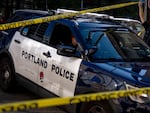 A Portland police officer lets a police car through caution tape blocking off the area surrounding the U.S. Immigration and Customs Enforcement building before U.S. Department of Homeland Security Secretary Kristi Noem visits to Portland on Tuesday, Oct. 7, 2025.