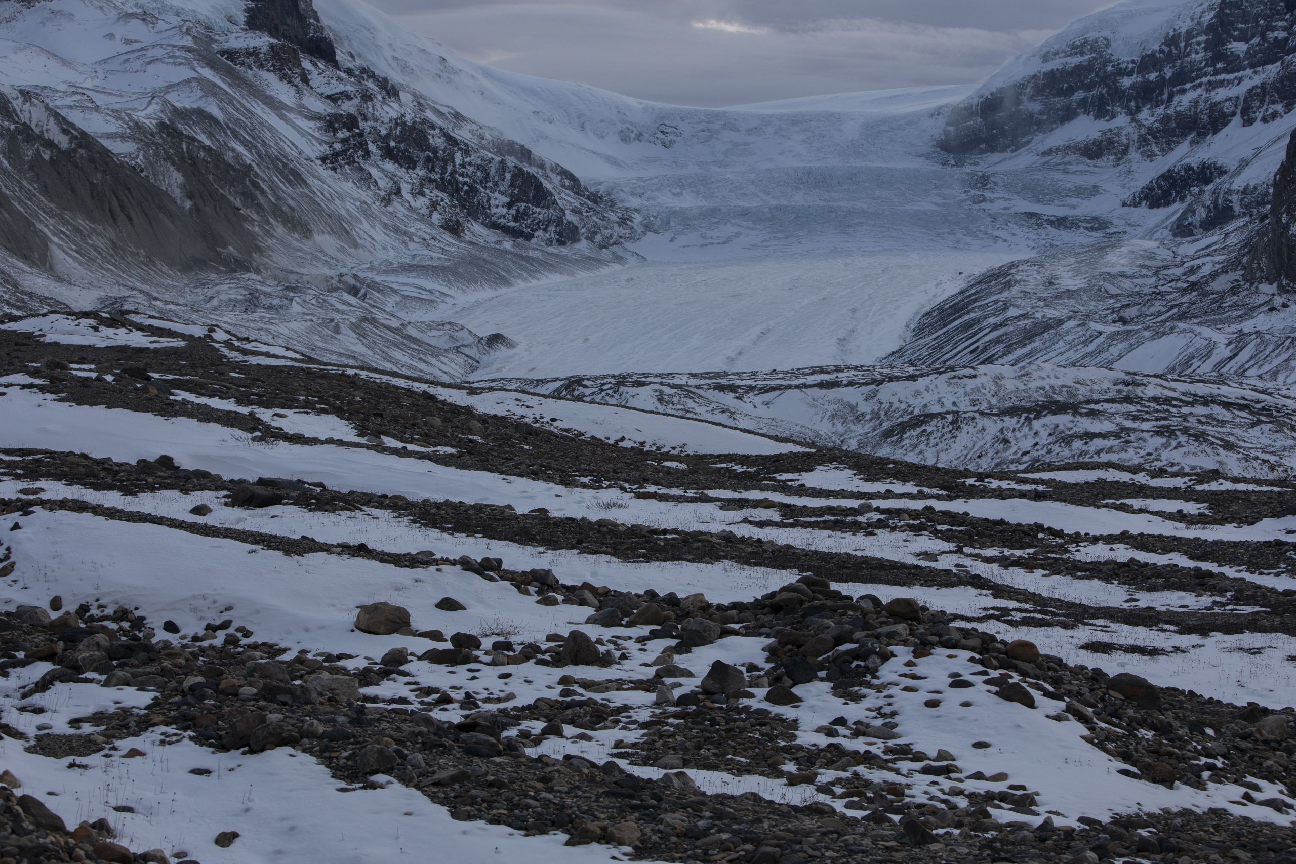 A grey photo of the Athabasca glacier shows exposed rock and snow