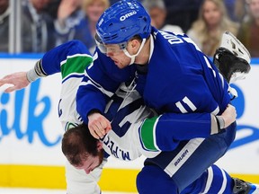 Maple Leafs forward Max Domi (top) and Canucks forward Marcus Pettersson fight during second period NHL action in Toronto, Saturday, Jan. 10, 2026.