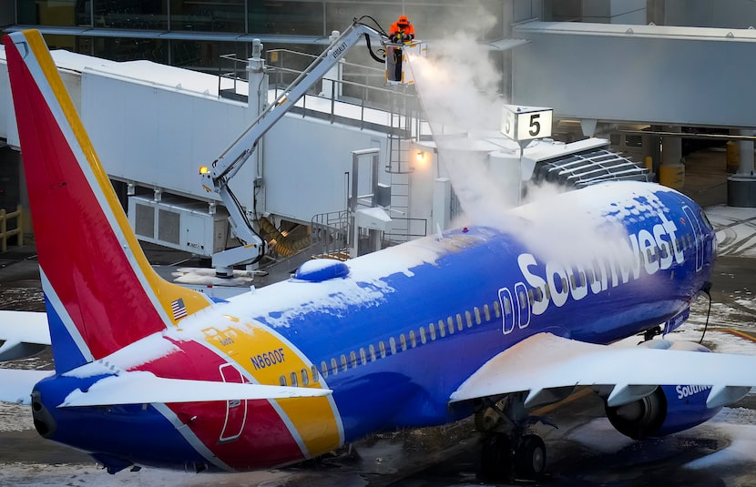 A worker sprays deicing fluid on a Southwest Airlines plane at the gates of Dallas Love...