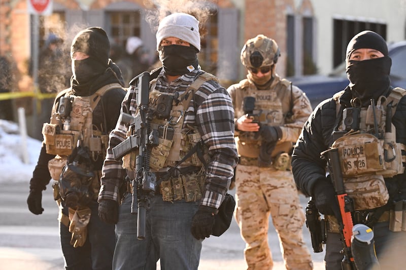 Federal agents look on as demonstators gather