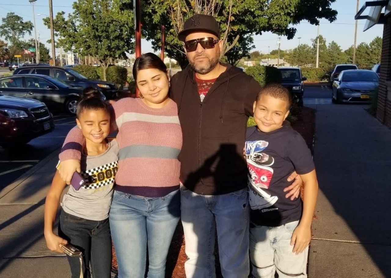 The family has their arms around each other posing for a photo.