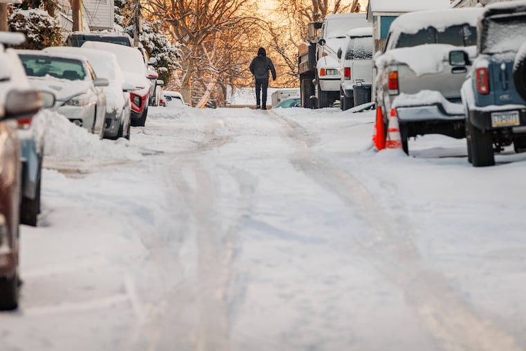 A Pedestrian walks on the snow and ice in Manayunk Monday. More snow is possible this weekend.