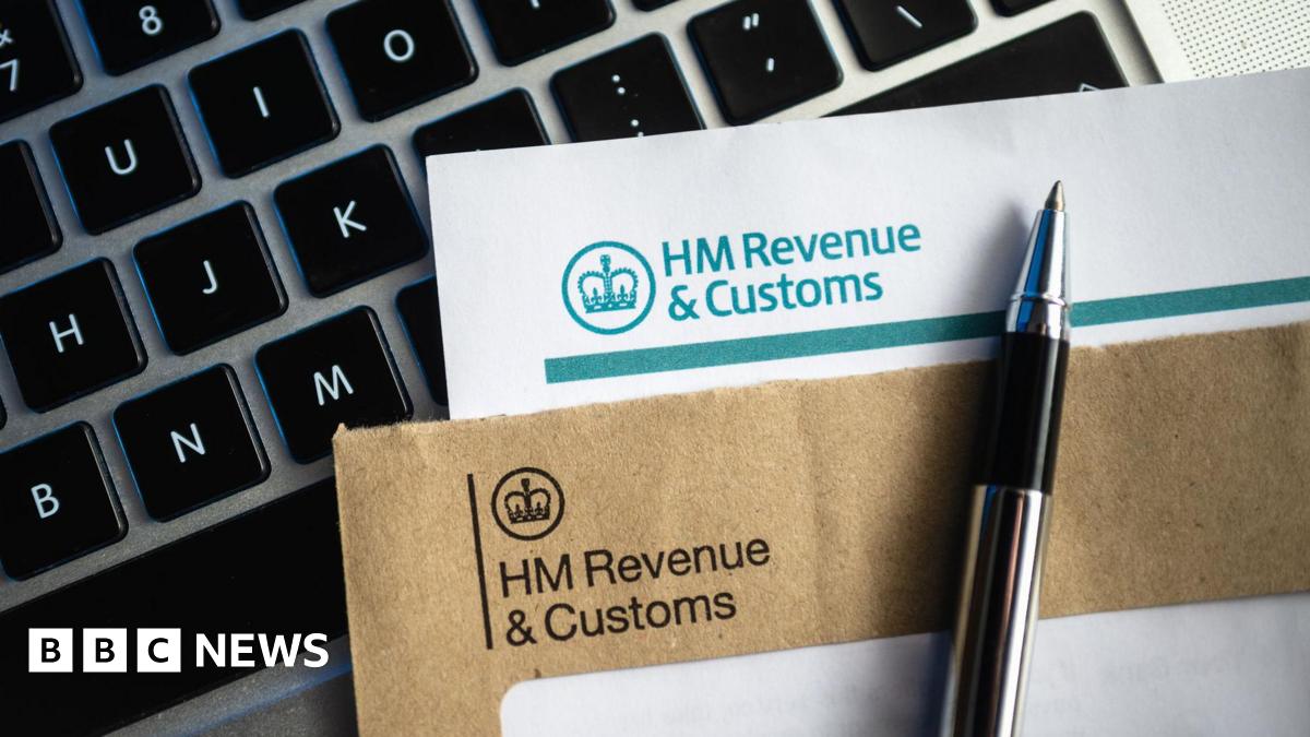 An HMRC-headed envelope and letter with a pen on top and a computer keyboard underneath.