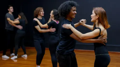 Getty Images Couples smile learning salsa at a dance studio