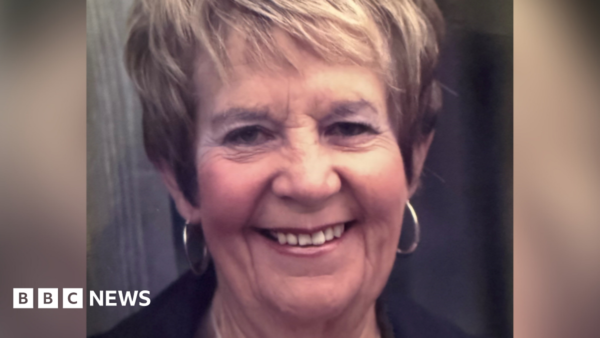 Ms Breed, who has short dark blonde hair and wears hoop earrings, smiles at the camera.