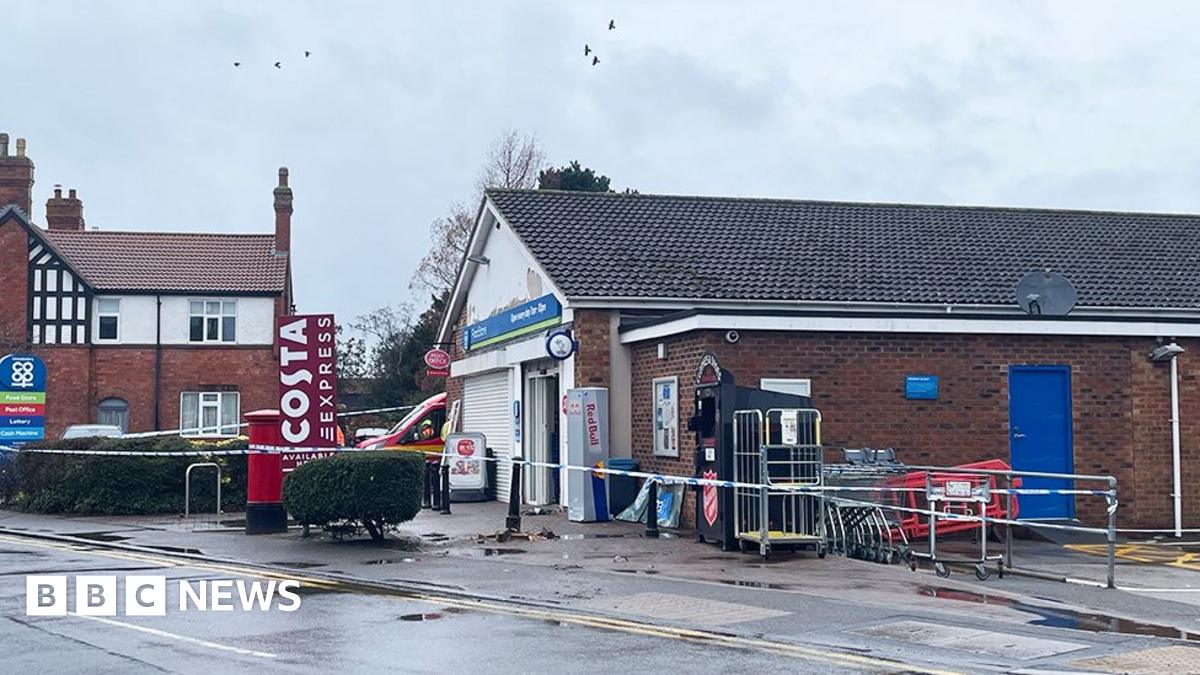 The Co-op store in Billinghay. It is a small, single-storey brick building with a pitched roof. At the front is a forecourt with a tree and bushes and a red post box and a blue Co-op sign listing the services. Police tape surrounds the shop and the white window shutter is down.