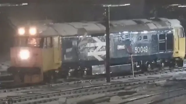 A blue and yellow locomotive on the train in the snow