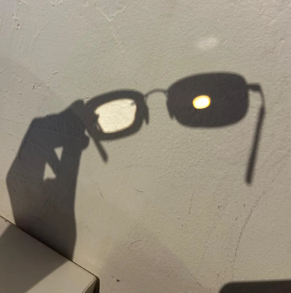 Shadow of eyeglasses on a wall, creating a playful visual effect