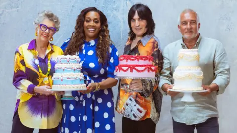 Channel 4/Love Productions/PA Media Prue Leith, Alison Hammond, Noel Fielding and Paul Hollywood posing together and holding up large colourful cakes in a publicity photo
