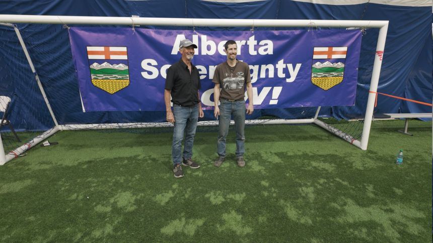 Albertans pose for a picture by a large sign demanding 