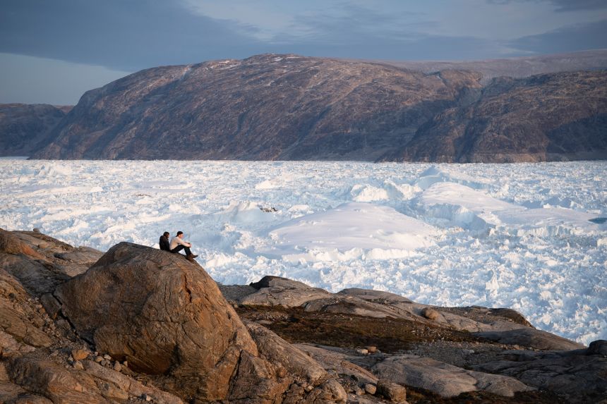 New York University student researchers sit on a rock overlooking the Helheim glacier in Greenland, August 16, 2019.
