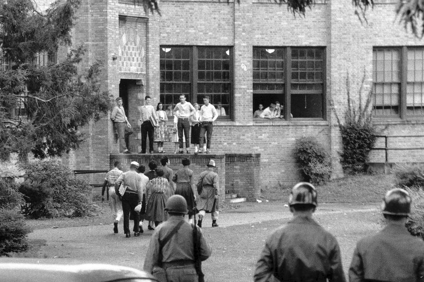 Seven members of the Little Rock Nine walk onto the campus of Central High School in Little Rock, Arkansas on October 15, 1957, with a National Guard escort.
