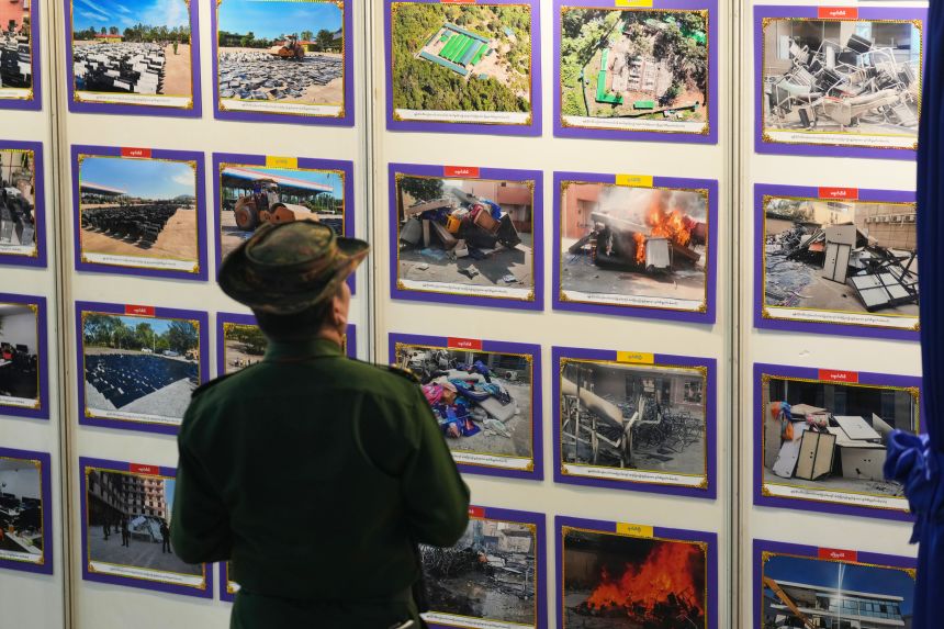 A Myanmar military officer looks at photos displayed during a news conference on national efforts to eliminate online scams in Yangon, Myanmar, on December 14, 2025.
