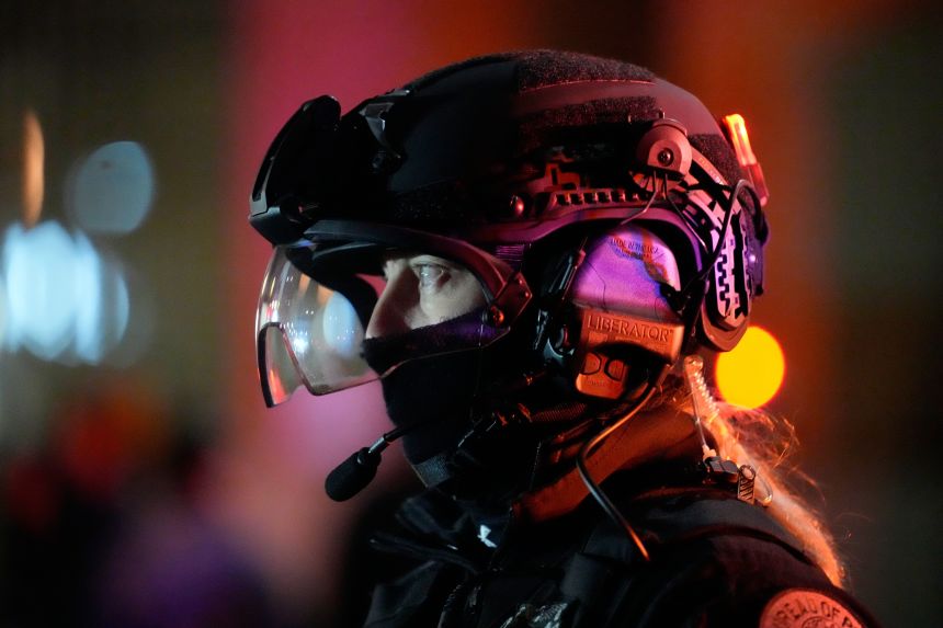 A Portland police officer stands outside the US Immigration and Customs Enforcement facility in Portland, on Thursday.