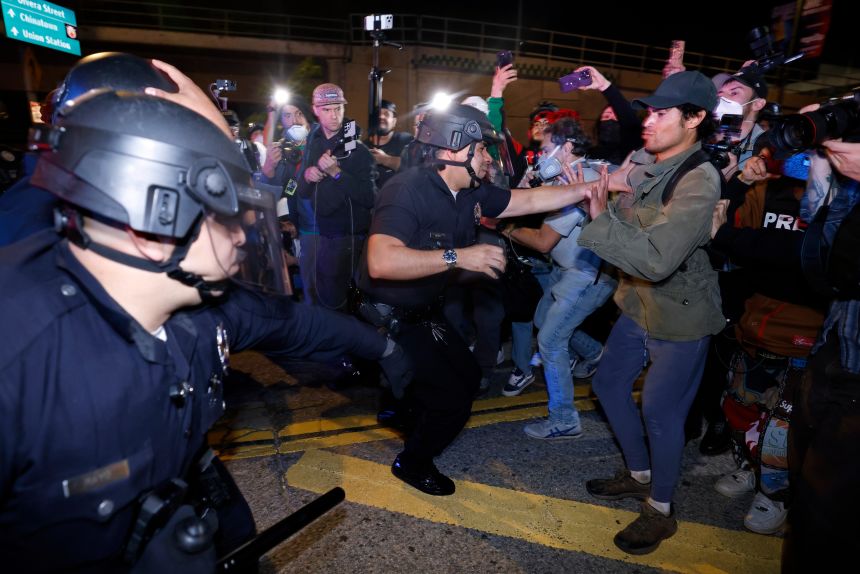 LAPD officers and protesters confront each other during a demonstration in front of the Metropolitan Detention Center calling for an end to federal immigration enforcement operations on Saturday.