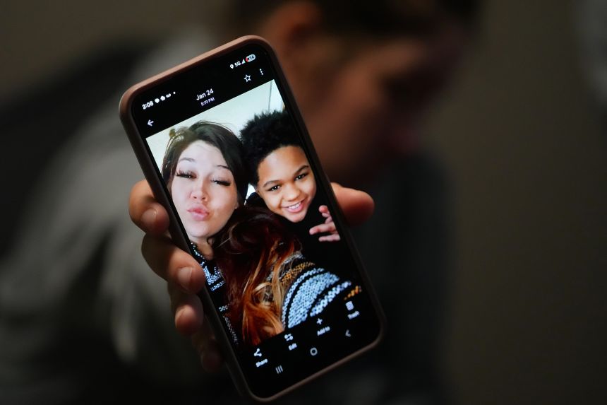 Cheyenne Hangaman shows a photograph of her and her son, EJ, 9, who along with his two brothers Kaleb, 8, and Howard, 6, died Monday after falling into an icy pond in Bonham, Texas.