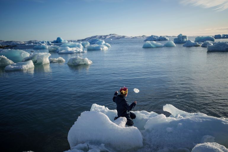 A boy throws ice into the sea.