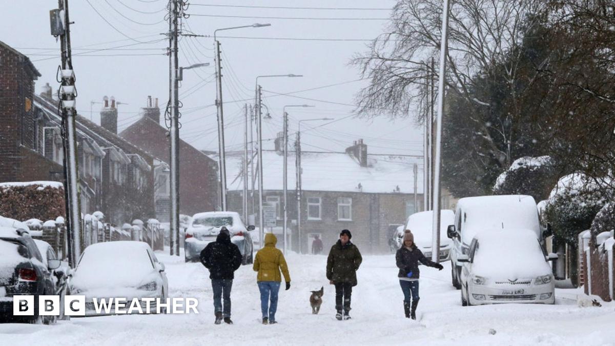 People and a dog walk through thick snow blanketing a residential street in West Kyo, County Durham