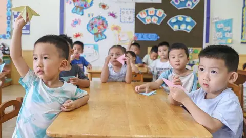 Getty Images Children sitting around a classroom table participate in a game at a summer day care class in Nanchang, China