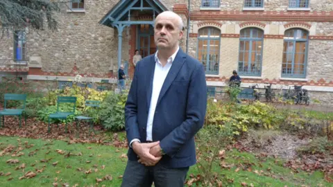 Prof Xavier Crettiez stands in a garden at Sciences Po Saint-Germain 