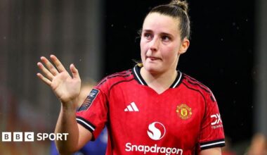Ella Toone gives a signal with her right hand as she wears Manchester United's large red home shirt
