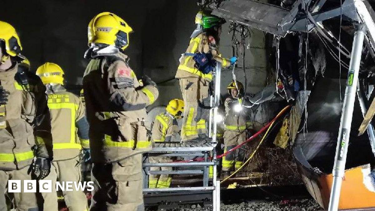 Donald Trump and Keir Starmer sit in a formal drawing room setting  on arm chairs with US and UK  flags behind them. Both have serious expressions and are looking out and not at each other.