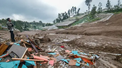 EPA A villager stands on the debris of damaged houses after a landslide affected the area in Pasirlangu village, West Bandung, West Java Province, Indonesia, 24 January 202