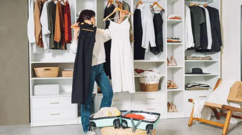 Getty Images Woman packing a suitcase for a trip in the dressing room 