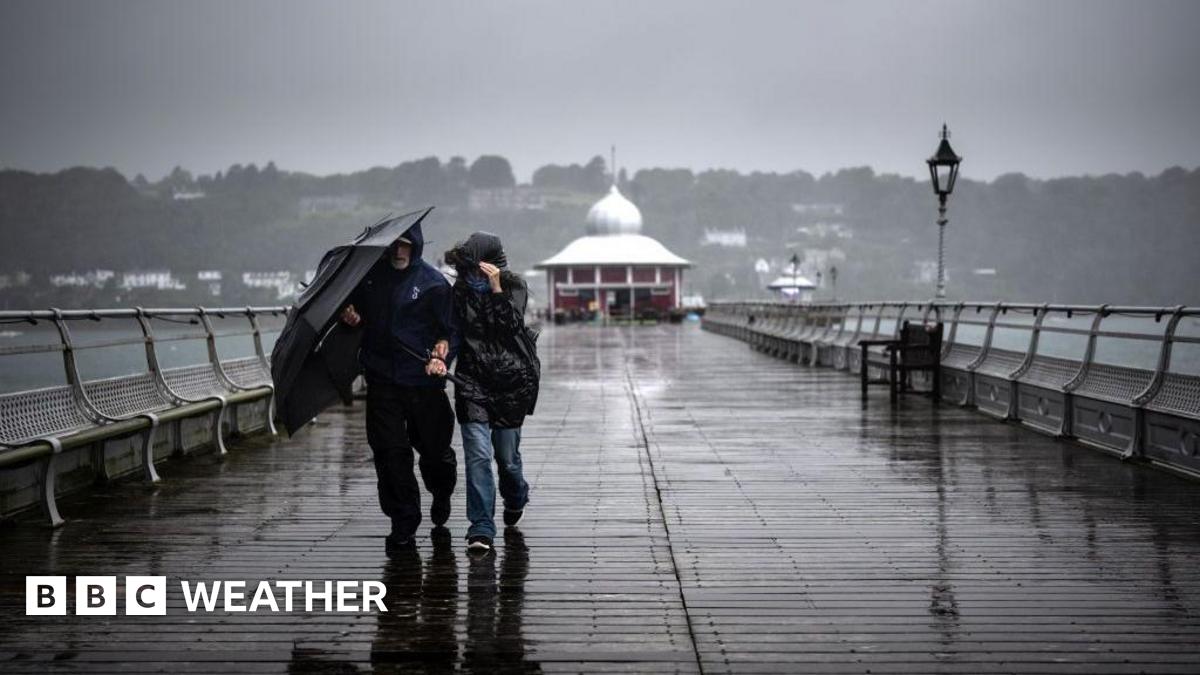 People walking along a pier with an umbrella on a wet and windy, grey day