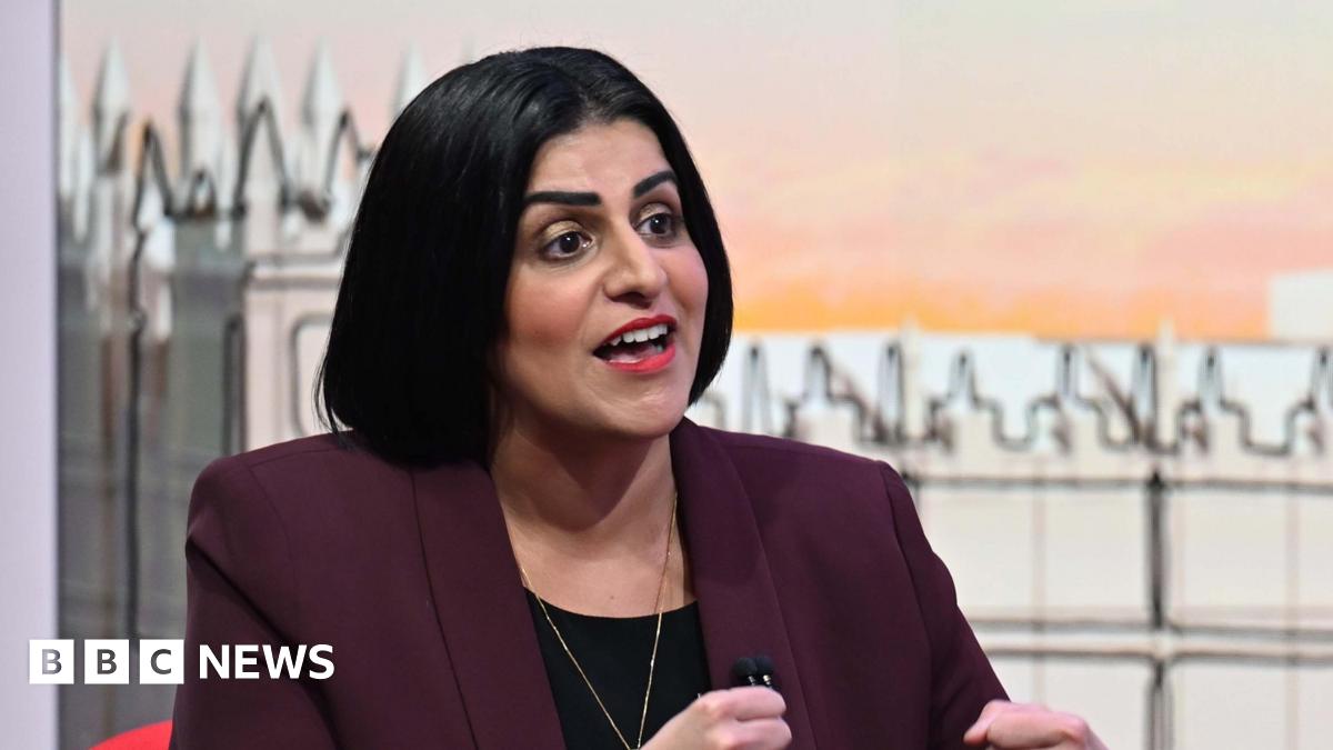 Home Secretary Shabana Mahmood wearing a maroon jacket over a black top. Her mouth is open as she talks. Behind her is a TV set with an illustration of the Houses of Parliament on it.
