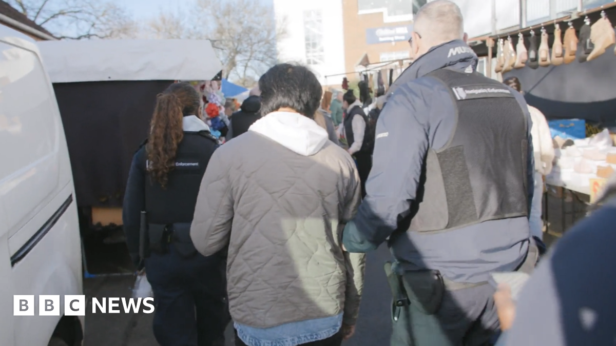 Two immigration enforcement officers escort a man through a market at Kempton Park racecourse in Surrey on 11 December.