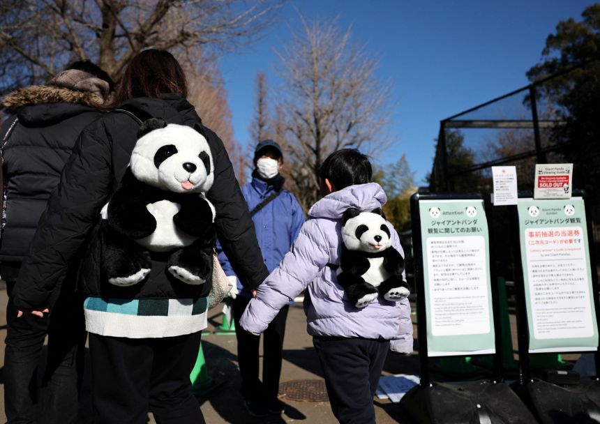 Visitors carry backpacks featuring giant pandas as they wait to see four-year-old giant pandas Xiao Xiao and Lei Lei, at Ueno Zoo during the last viewing day.