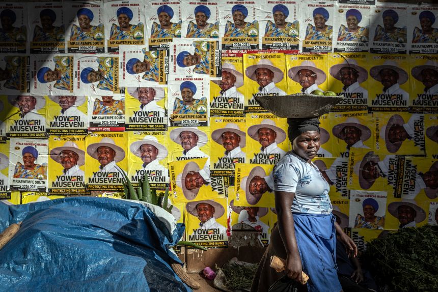 A street vendor walks past a wall decorated with electoral posters supporting Uganda's incumbent president and National Resistance Movement (NRM) presidential candidate Yoweri Museveni, ahead of the 2026 Ugandan general elections, in Kampala on January 10.