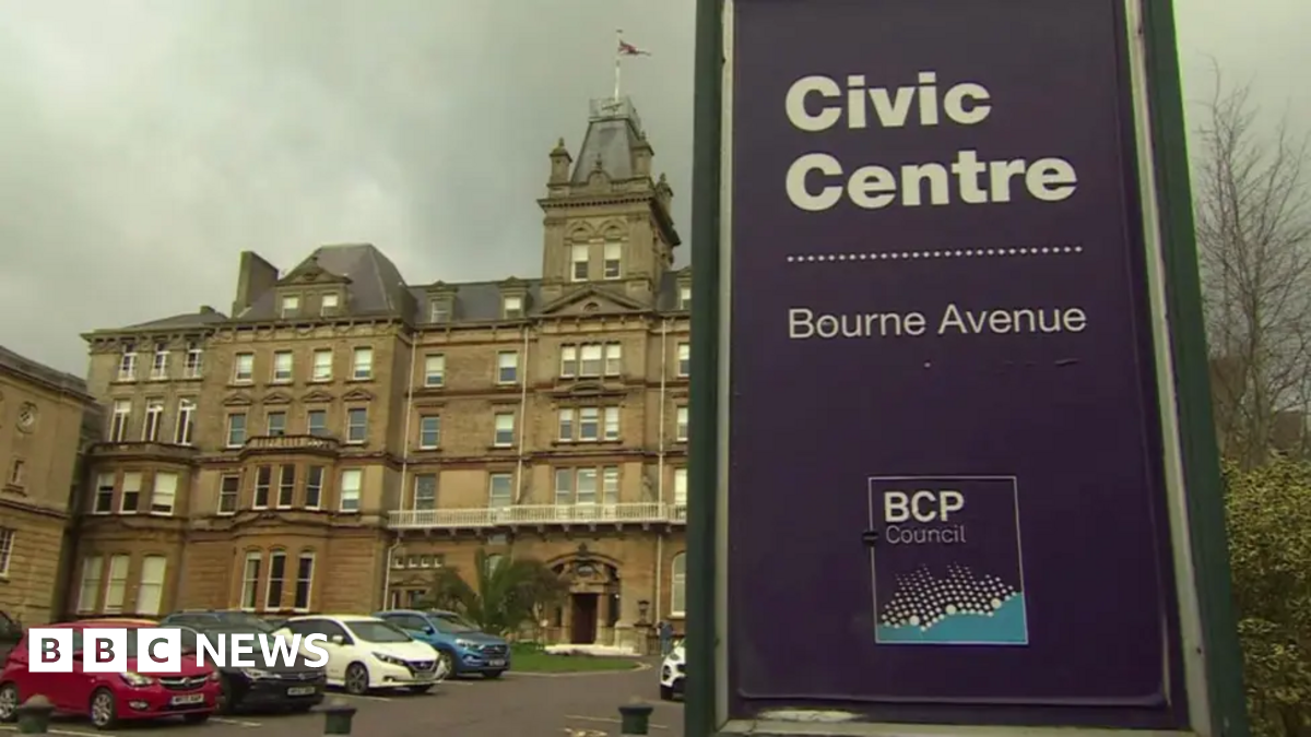The headquarters of BCP Council in Bournemouth. A council sign, the front door of the town hall and cars parked are all visible