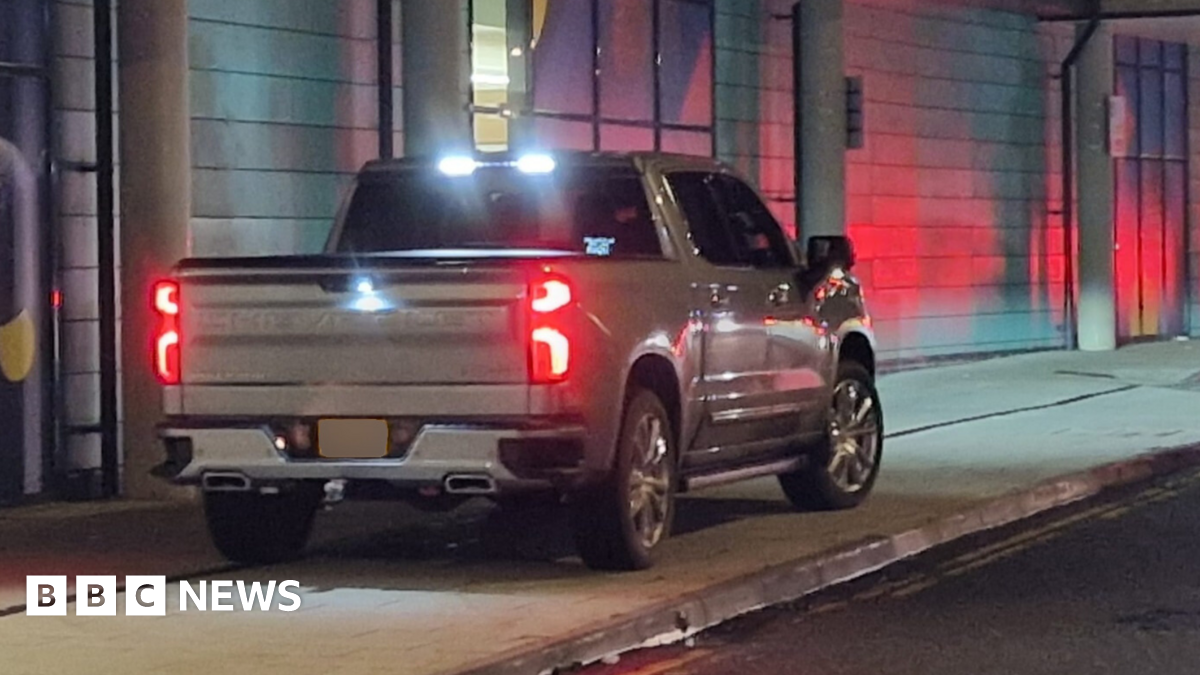 A grey pickup truck parked on a pavement.