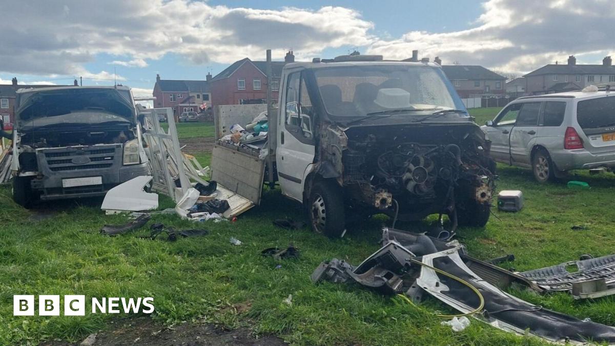Three battered vehicles parked on a grass area with parts scattered across the field.