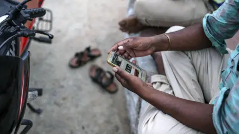 Getty Images A man looks at his mobile phone in Manajipet village in the district of Gadwal, Telangana, India, on Monday, June 11, 2018. 