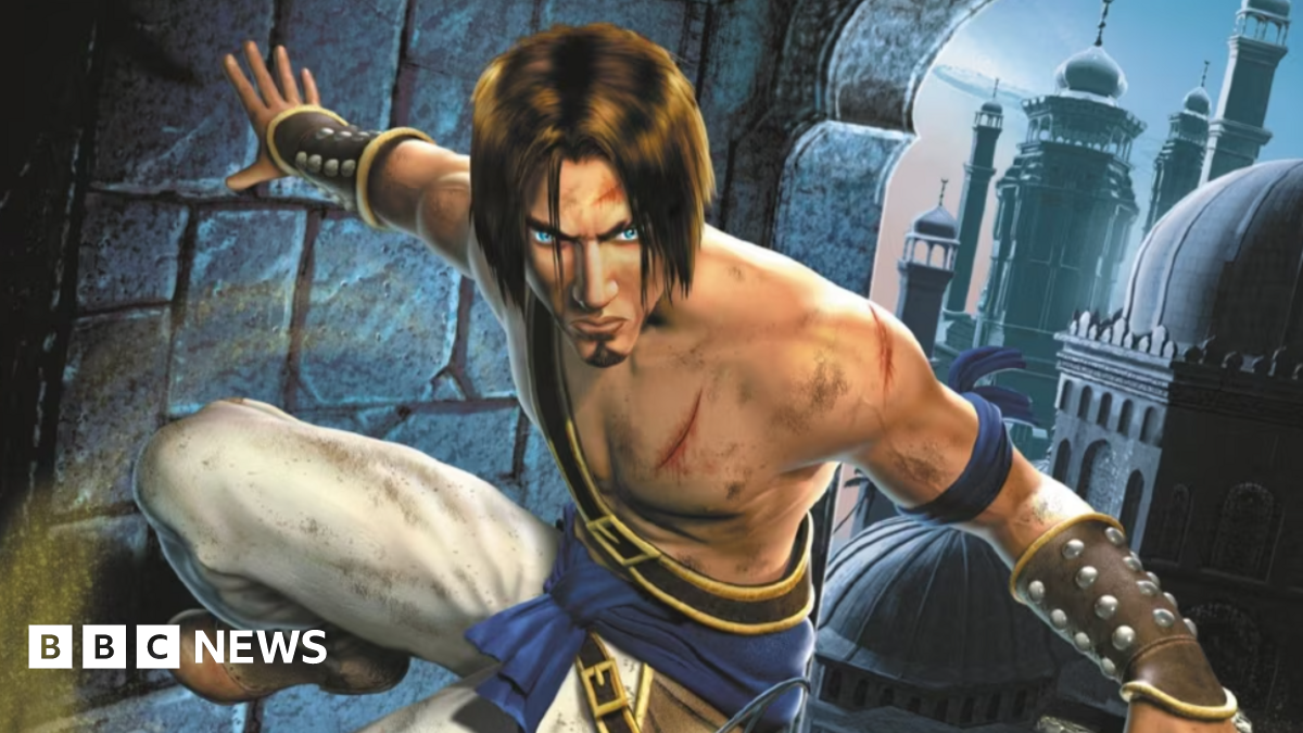 A video game character wearing garb referencing historic Middle Eastern attire. He has blue eyes and a long brown fringe. In the background, a city scene with buildings in a historic Persian style.