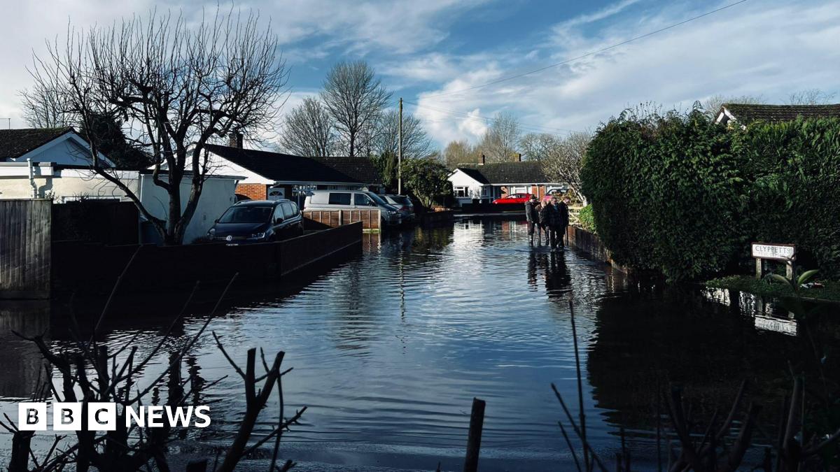 Flooded street at Winterborne Kingston in Dorset. People are seen walking through the water.
