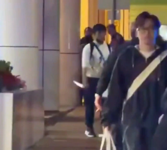 A screengrab of a video, it shows a man holding a large knife on a street