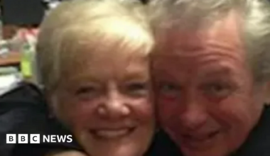 Sheila Jackson, who has blonde hair and is 83 years old, is photographed hugging her partner Peter Greener, 77, who has swept-back grey hair.