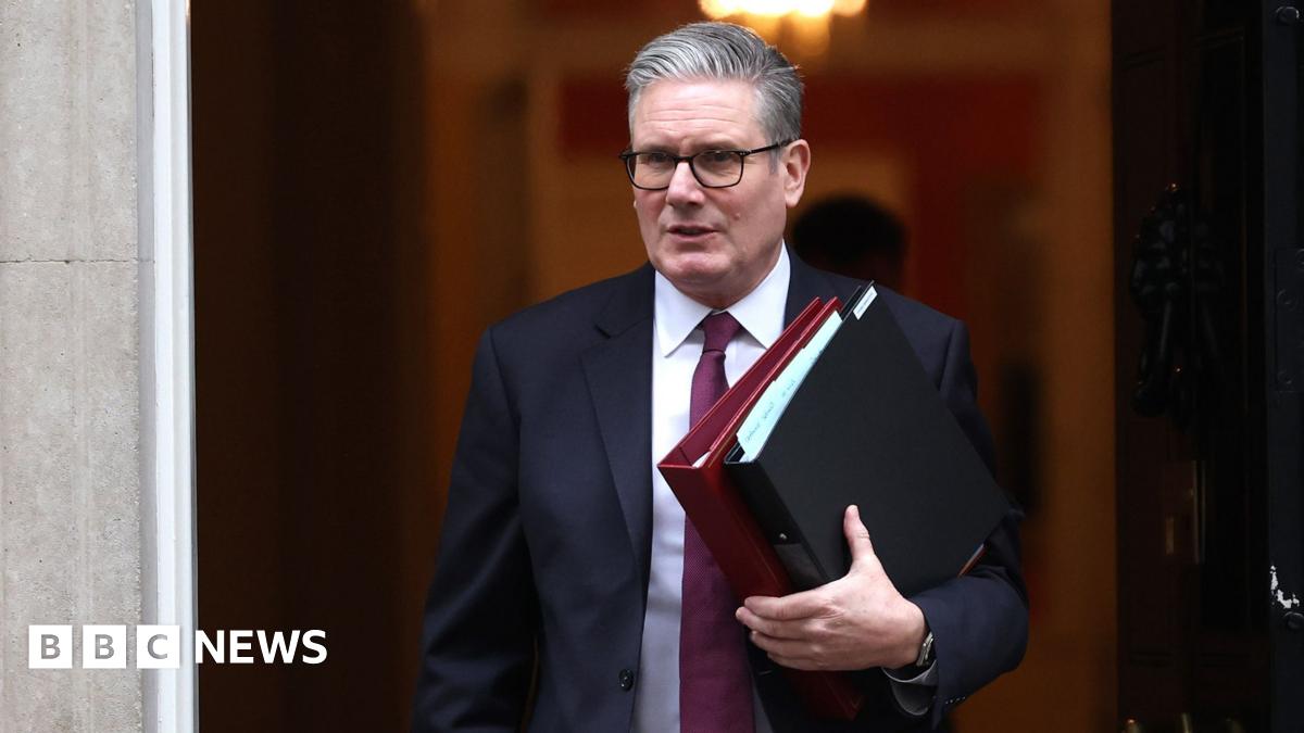Starmer looks away from camera as he exits Downing Street holding files while wearing a suit and tie before PMQs on Wednesday.