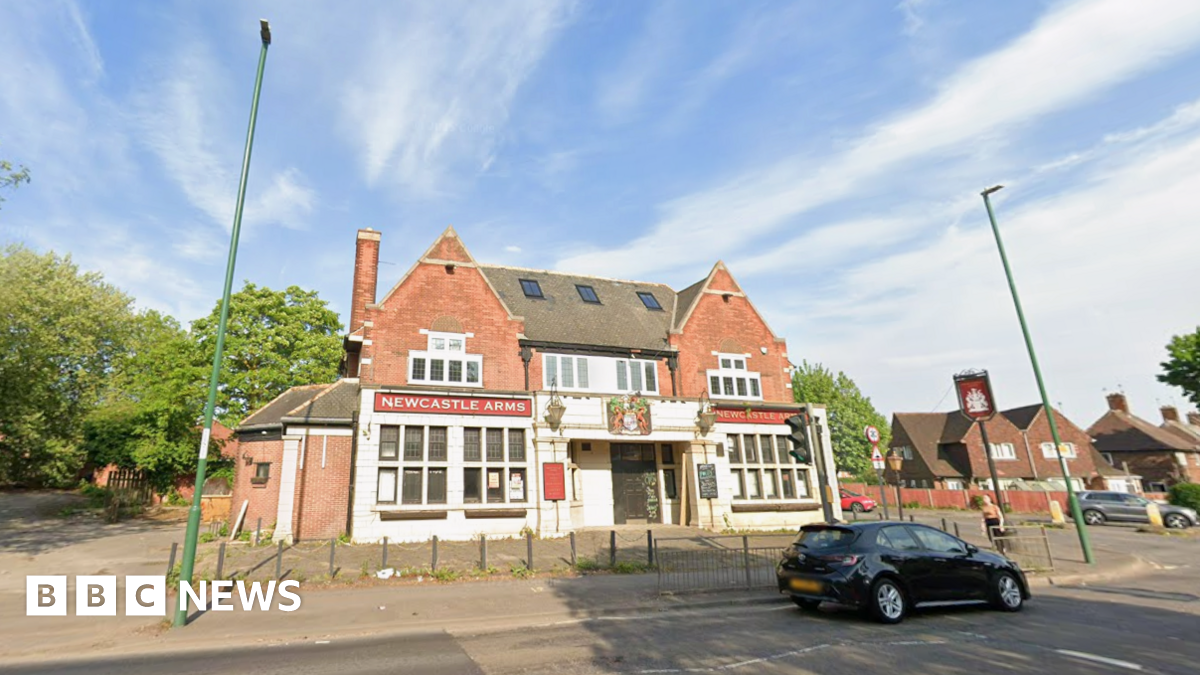The Newcastle Arms pub with a black car in front of the former pub with a blue sky above