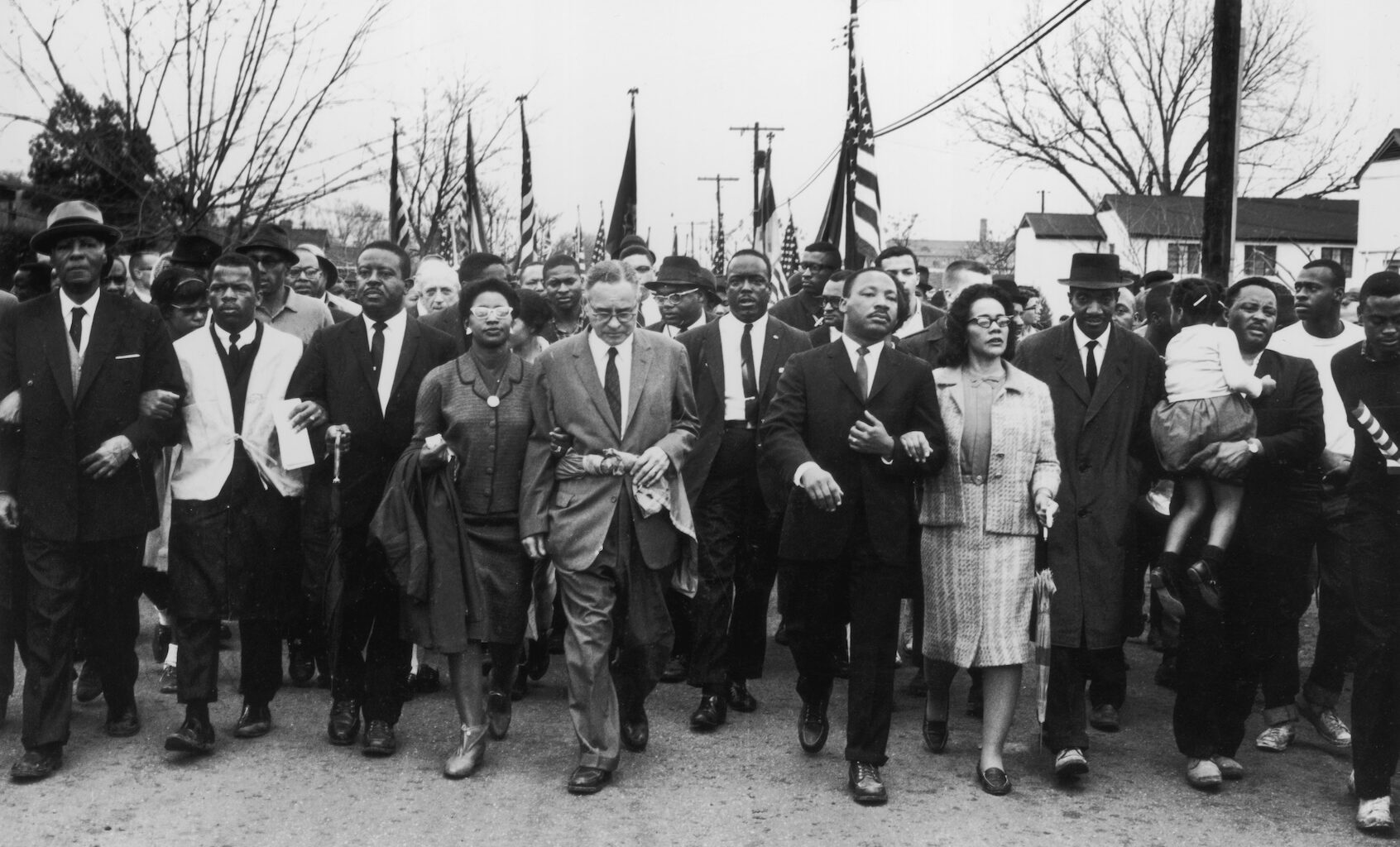 March 1965:  American civil rights campaigner Martin Luther King (1929  - 1968) and his wife Coretta Scott King lead a black voting rights march from Selma, Alabama, to the state capital in Montgomery;  among those pictured are, front row, politician and civil rights activist John Lewis (1940 – 2020), Reverend Ralph Abernathy (1926 - 1990), Ruth Harris Bunche (1906 - 1988), Nobel Prize-winning political scientist and diplomat Ralph Bunche (1904 - 1971), activist Hosea Williams (1926 – 2000 right carrying child). (Photo by William Lovelace/Daily Express/Hulton Archive/Getty Images)