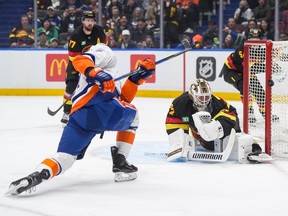 Vancouver Canucks goalie Kevin Lankinen, right, watches the puck as New York Islanders' Maxim Tsyplakov puts a shot off the side of the net during the first period at Rogers Arena on Monday night.