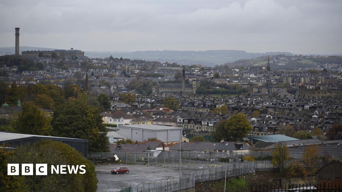 The Bradford skyline, viewed on a cloudy day. Rows of housing, trees and industrial buildings can be seen.