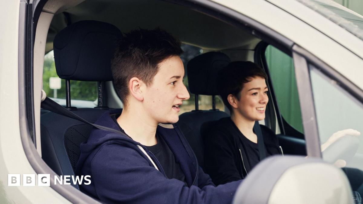 A woman with long blonde hair and a denim jacket in a room with white walls