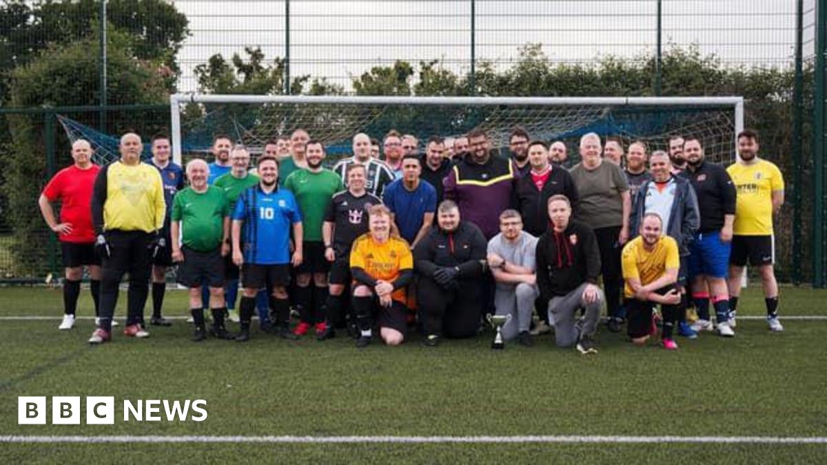 Roughly three dozen football players standing for a group photo in front of a goal