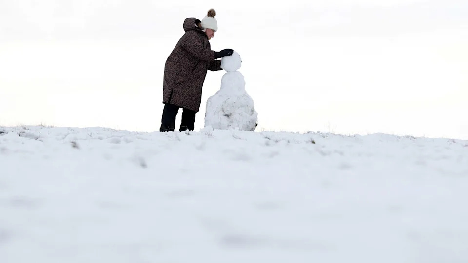 A woman builds a snowman at Bradgate Park in Newtown Linford, central England on January 9, 2026. The United Kingdom, France and Germany shivered through severe winter weather on January 9, with tens of thousands of homes suffering the cold snap without power. (Photo by Darren Staples / AFP via Getty Images)